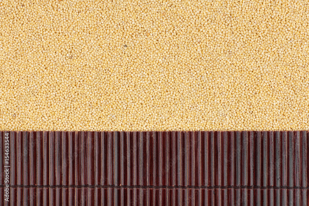 Fototapeta premium Beautiful bamboo mat on millet grains as agricultural background.