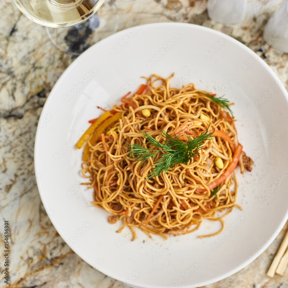Flat egg noodles with pork slices served on white plate with white garlic and red spicy sauce Flat egg noodles with pork slices served on white plate with white garlic and red spicy sauce