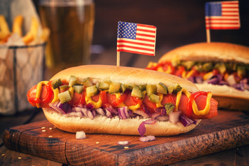 American hot dog with pickles,onions, ketchup, mustard and french fries at a Picnic for 4th of July 