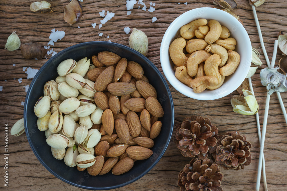 appetizer roasted healthy delicious salt pistachios, cashew nuts and almonds food in black bowl on wooden table background