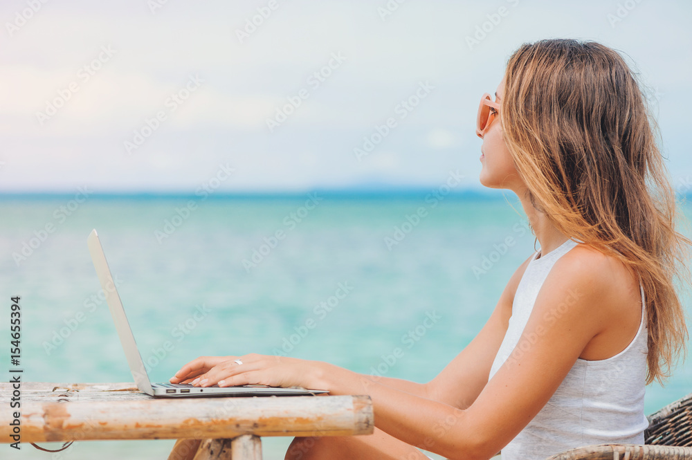 Young sexy woman using laptop on the beach. Freelance work