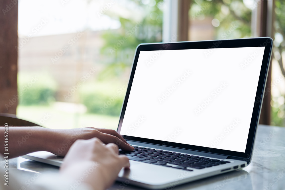 Mockup image of hand using laptop with blank white screen on vintage wooden table in cafe Mockup image of hand using laptop with blank white screen on vintage wooden table in cafe
