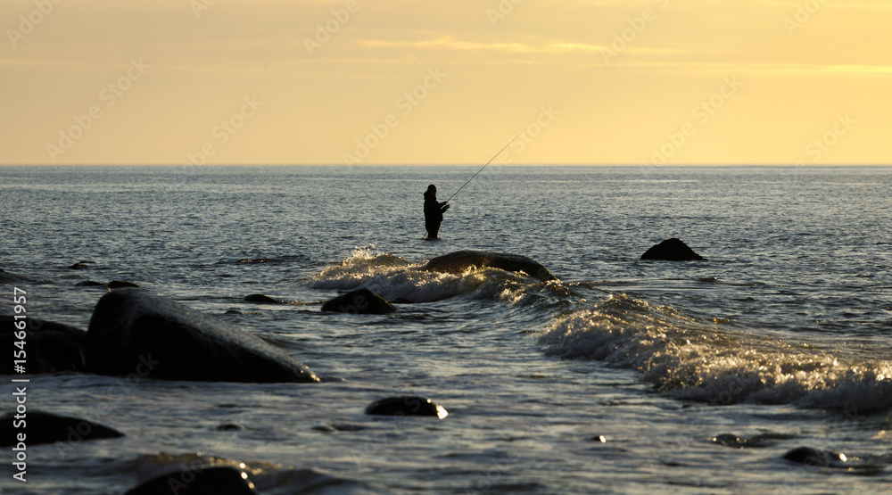 im Wasser stehender Angler - beim Sonnenuntergang