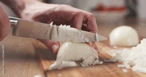 Tableau sur toile man cutting white onion with knife