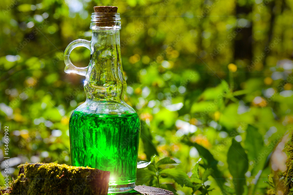 Green herbal potion On a mossy tree. Herbal elixir. Magic Potion. Homeopathic medicine. Green herbal potion On a mossy tree. Herbal elixir. Magic Potion. Homeopathic medicine.