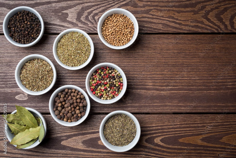 Herbs and spices in white bowls on wooden table