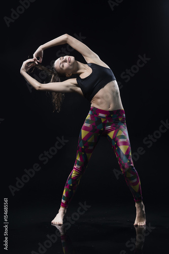 The girl dances on the floor covered with water on a black background