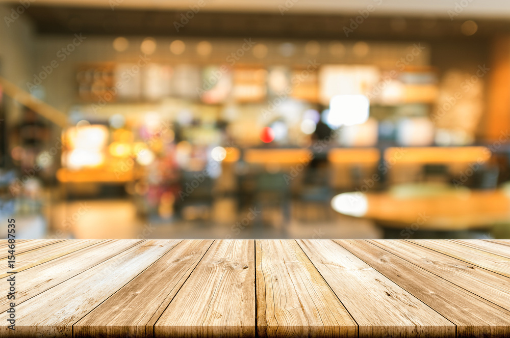 Empty wooden table top with blurred coffee shop interior background.