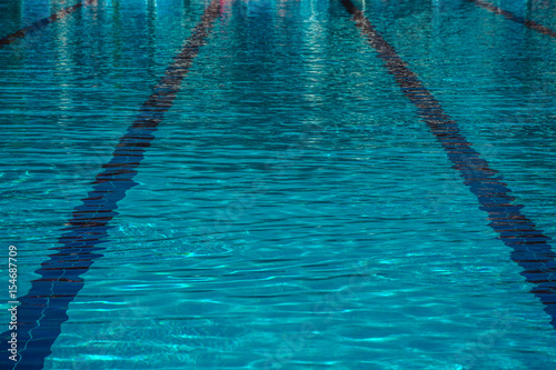 The surface of turquoise water in the pool as a background. Clean and bright water in swimming pool. Ripple water in swimming pool with sun reflections.