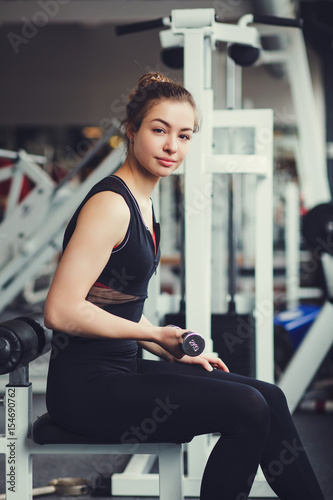 Beautiful sports girl picks up dumbbells in the gym