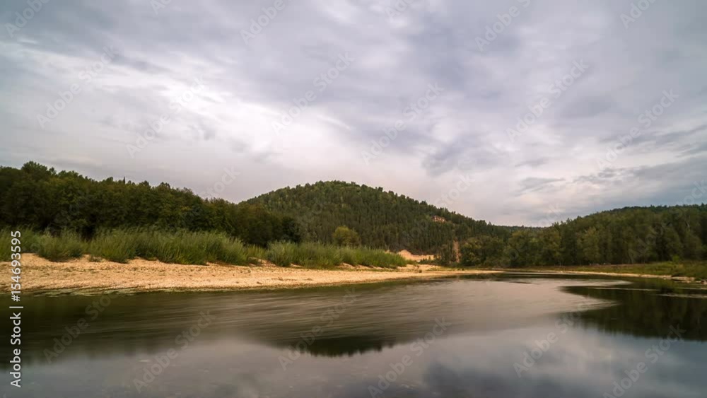 Time lapse of moving gray clouds reflecting on lake surrounded by a mountain forest. Time lapse of moving gray clouds reflecting on lake surrounded by a mountain forest.