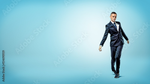 A businessman on blue background walking on unsteady legs like a broken doll.