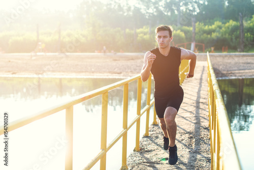 Fototapeta Naklejka Na Ścianę i Meble -  Sporty young man jogger exercising working out at morning outdoors.