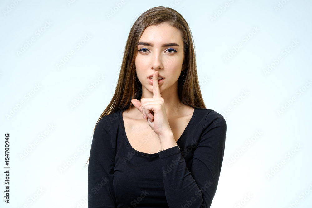 Keep silence! Beautiful young woman holding finger on lips Keep silence! Beautiful young woman holding finger on lips