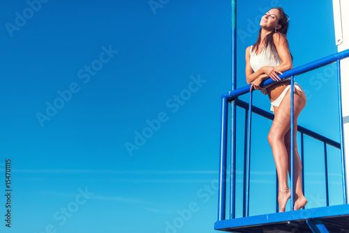 Portrait of beautiful young woman in bikini on beach sunbathing.