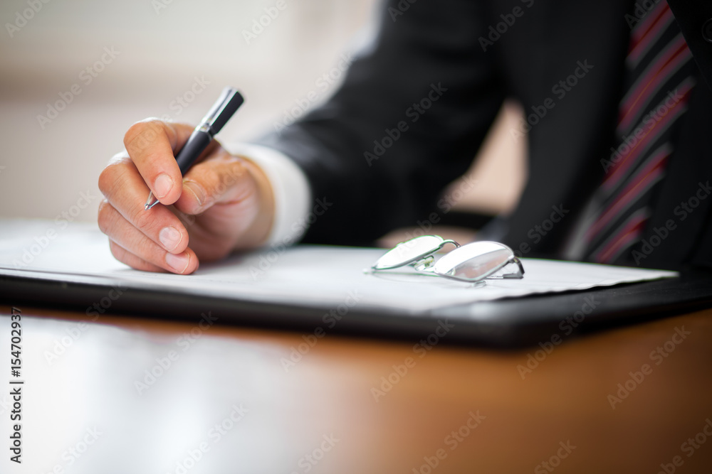 Businessman writing in a documen Businessman writing in a documen