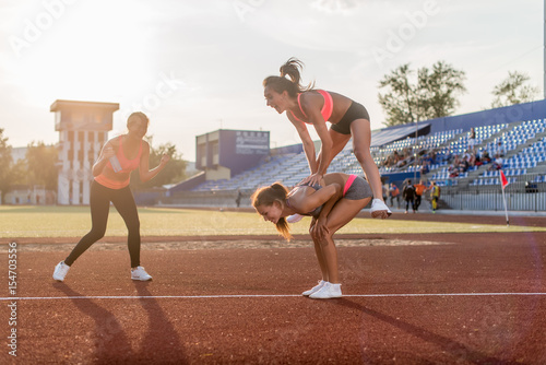 Fit women in the stadium playing leap frog. photo