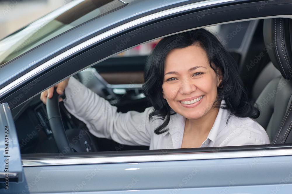 Beautiful mature woman checking out new cars at the dealership Beautiful mature woman checking out new cars at the dealership