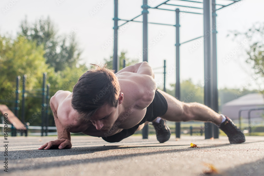 Athlete young man doing one-arm push-up exercise working out his upper ...