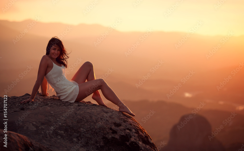 Schöne Frau in weißen Kleid sitzt auf Felsvorsprung
