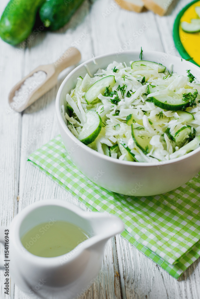 vegetarian Healthy food, light, low calorie fitness salad of fresh cucumbers, cabbage and dill with olive or sunflower oil, spices and salt on a light wooden background vegetarian Healthy food, light, low calorie fitness salad of fresh cucumbers, cabbage and dill with olive or sunflower oil, spices and salt on a light wooden background