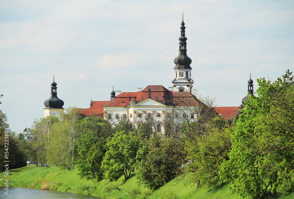 beautiful white monastery in Olomouc behind the green trees in spring, Czech Republic