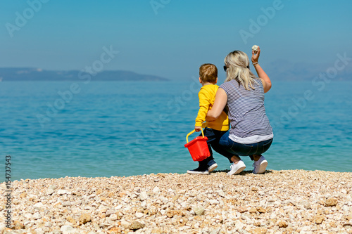 A happy mother and young child boy son having fun on a sunny beach