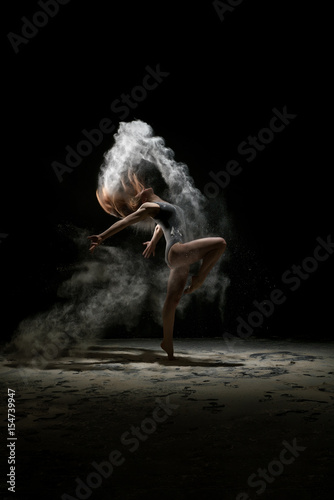 Girl dancing in a cloud of white dust studio portrait