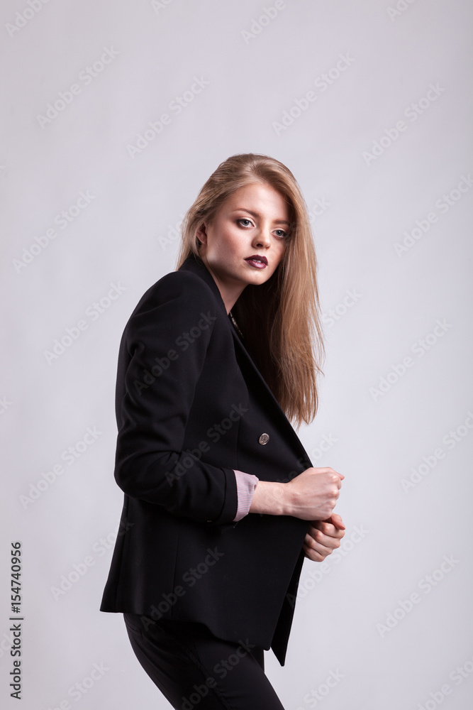 Styled sensual woman in fashion suit on gray background in studio photo. Elegant blonde Styled sensual woman in fashion suit on gray background in studio photo. Elegant blonde