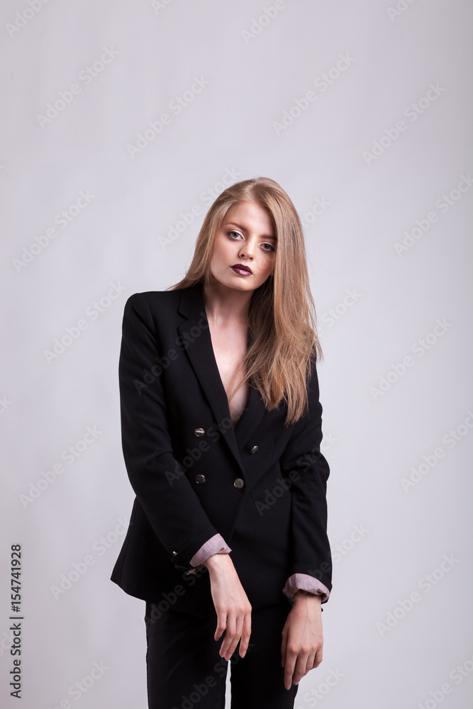 Styled gorgeous woman in fashion suit on gray background in studio photo. Elegant blonde Styled gorgeous woman in fashion suit on gray background in studio photo. Elegant blonde