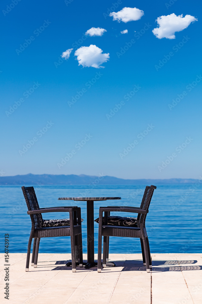 background of two chairs and beach and small bag and table place