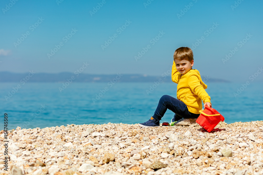 cute baby boy playing on the beach with water