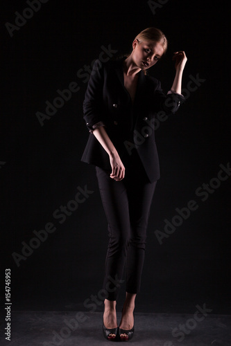 Woman in suit on black background in studio photo. Glamour and elegance