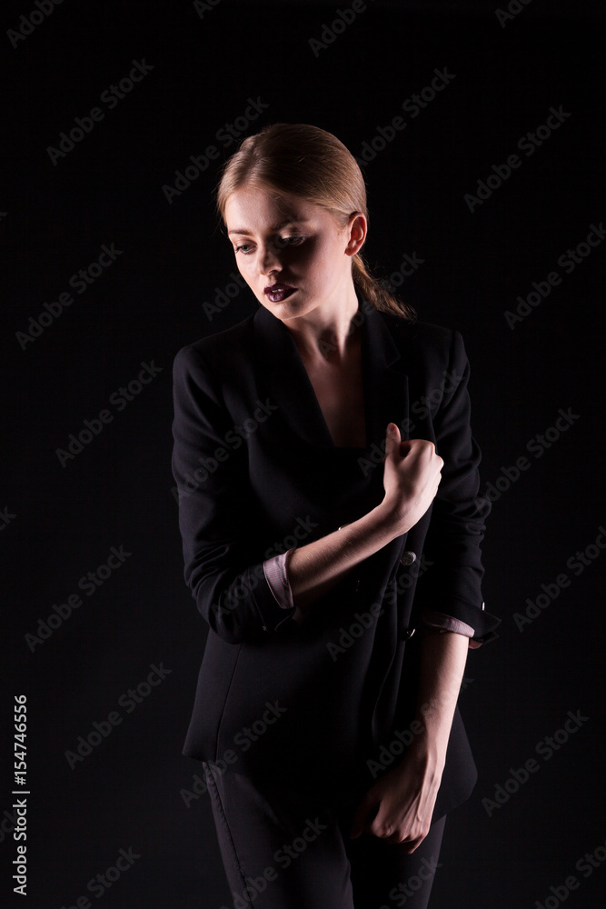 Woman in suit on black background in studio photo. Glamour and elegance