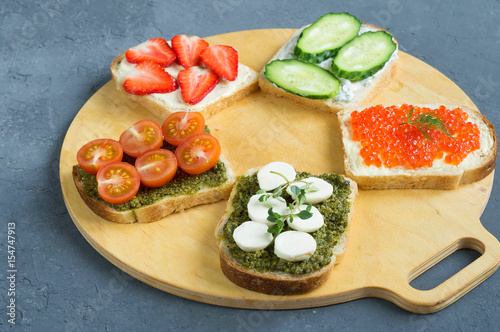 Healthy snack, healthy Breakfast, Bruschetta with pesto, mozzarella, red caviar and vegetables. Cottage cheese and strawberries.