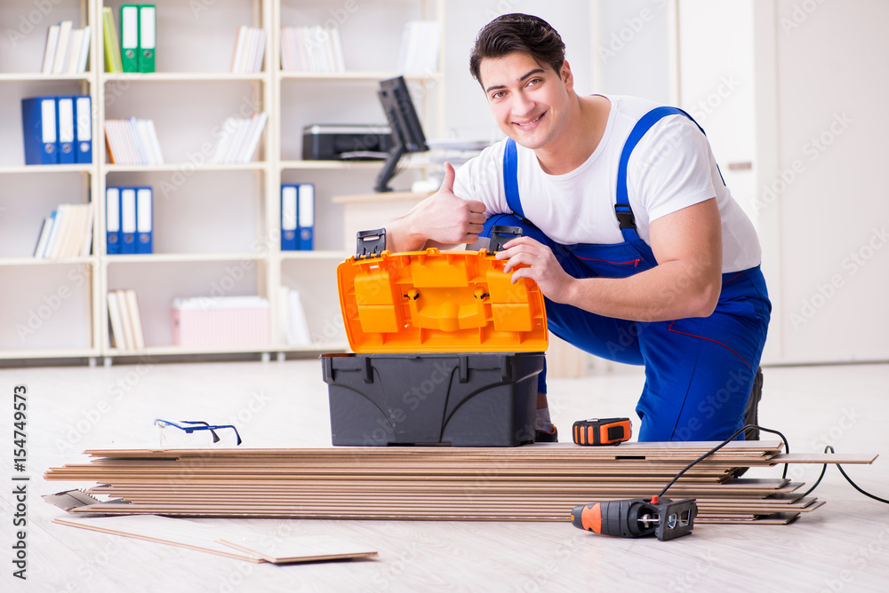 Young worker working on floor laminate tiles Young worker working on floor laminate tiles