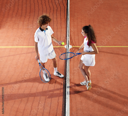 tennis players with racket and ball standing in front of the net © amedeoemaja