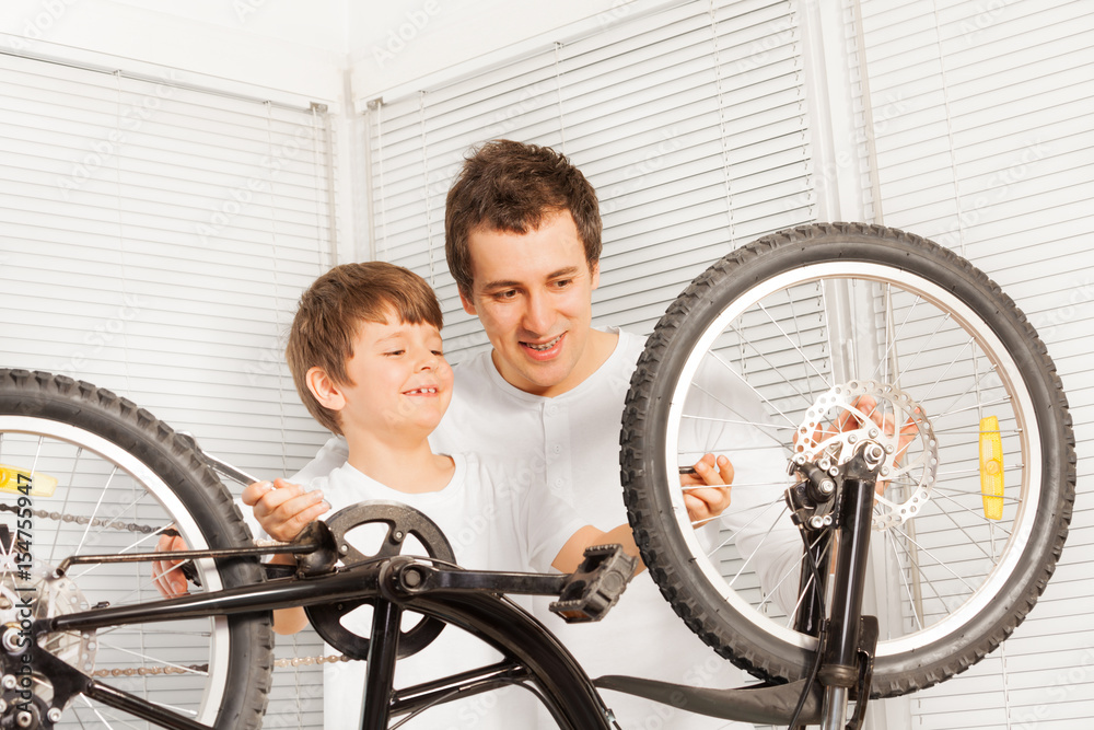 Dad showing his kid son how to repair bicycle Dad showing his kid son how to repair bicycle