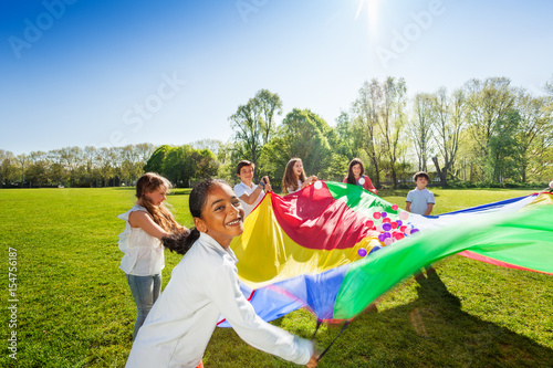 Happy boy waving colorful parachute with friends