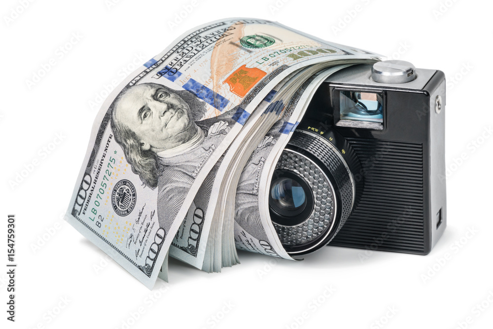 Old retro camera with a bundle of money lying on it, isolated on a white background