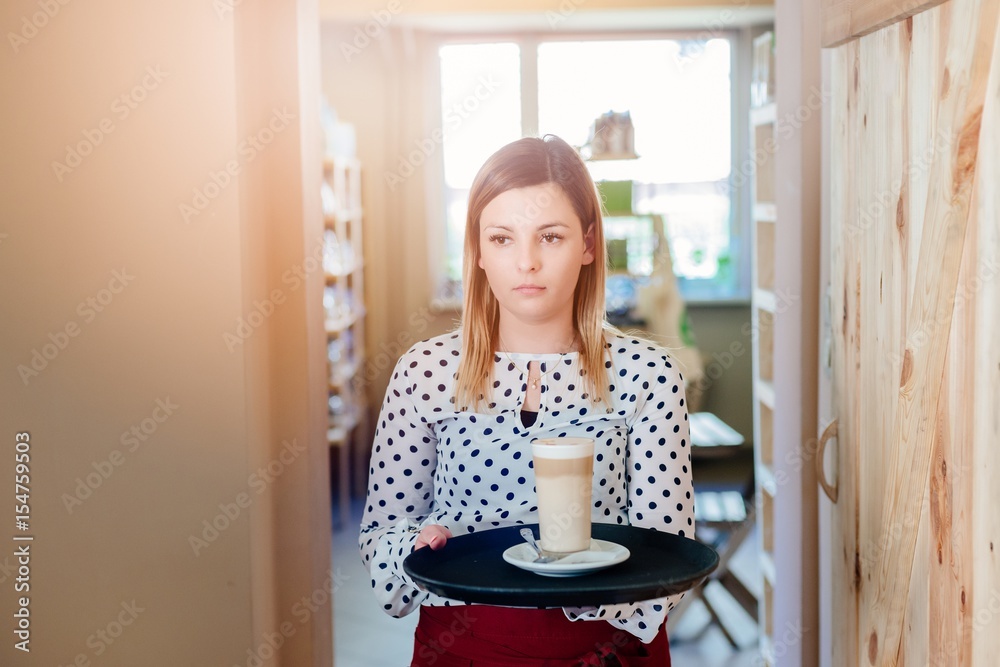 Waitress in the cafe carries a tray with cafe latte Waitress in the cafe carries a tray with cafe latte