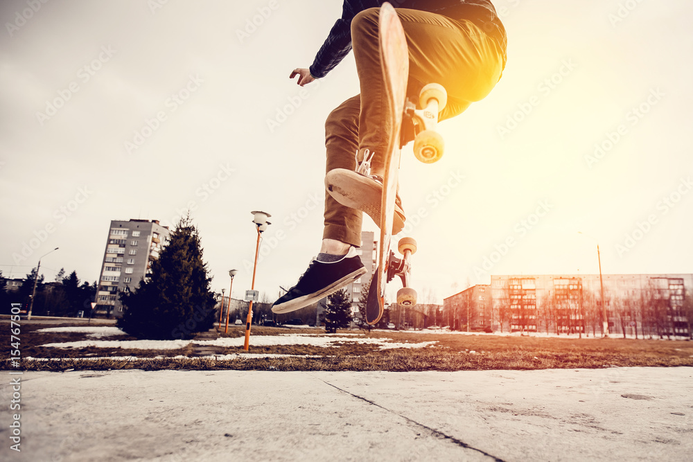Man young skateboarder legs skateboarding at skatepark On Sunset. Concept tricks and jumping on a skateboard