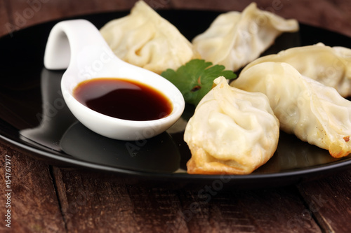 A plate of Japanese gyoza dumplings sitting on a rustic wooden table.