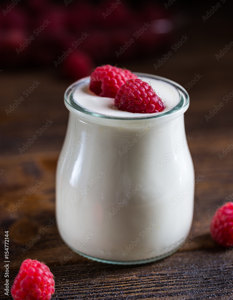 White yogurt with raspberries in glass bowl on rustic table. White yogurt with raspberries in glass bowl on rustic table.