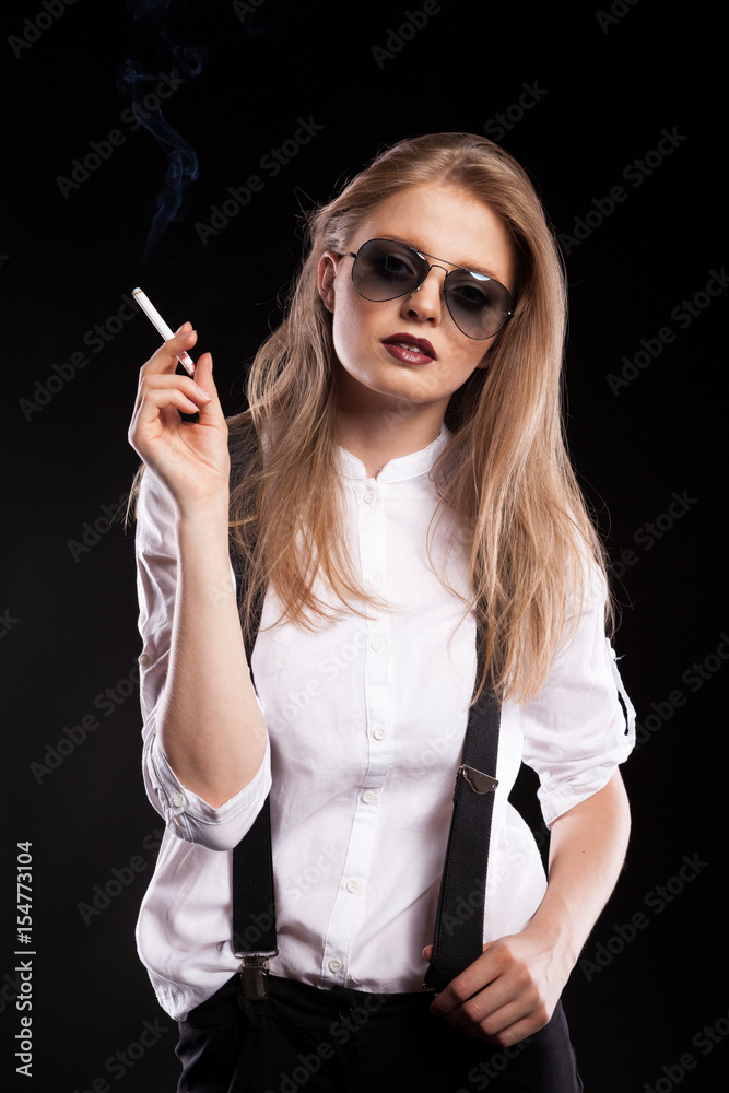 Obraz premium Blonde woman smoking on black background in studio photo