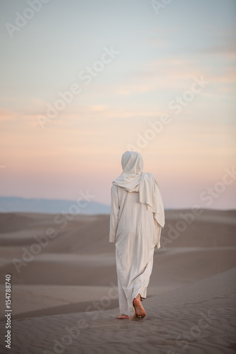 Jesus Christ walking through the sand at sunset with light pink and blue clouds, St. Anthony, Idaho