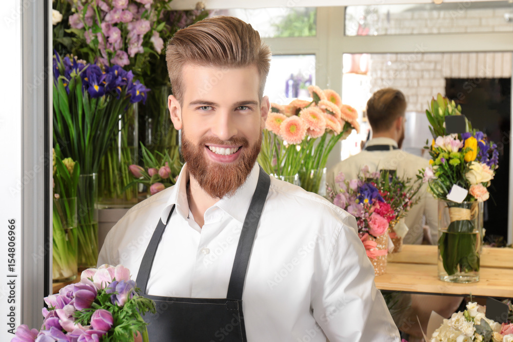 Young handsome florist with beautiful bouquet at flower shop