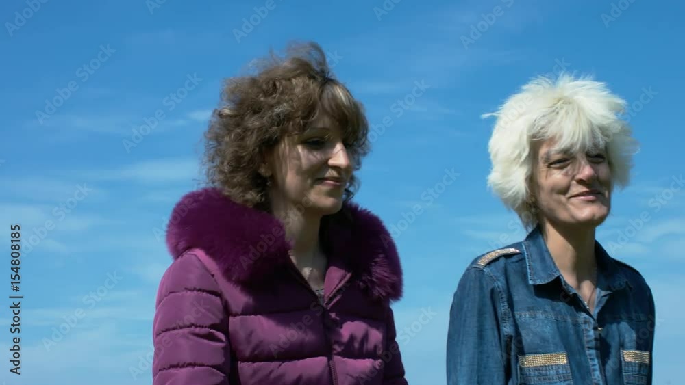 A Blonde Lady And Her Daughter Walking In The Nature, Enjoying The Sunshine On A Spring Day A Blonde Lady And Her Daughter Walking In The Nature, Enjoying The Sunshine On A Spring Day