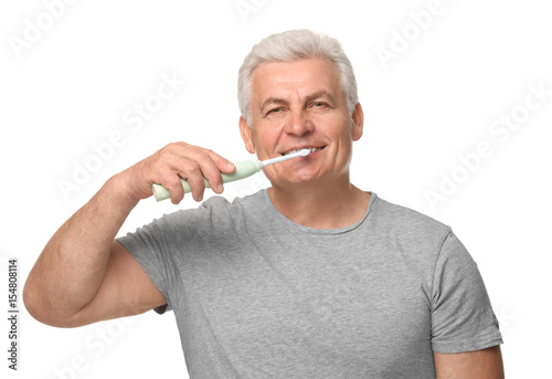 Senior man cleaning teeth on white background