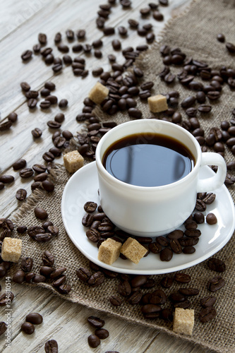 Black coffee in a mug and roasted coffee beans on a wooden background